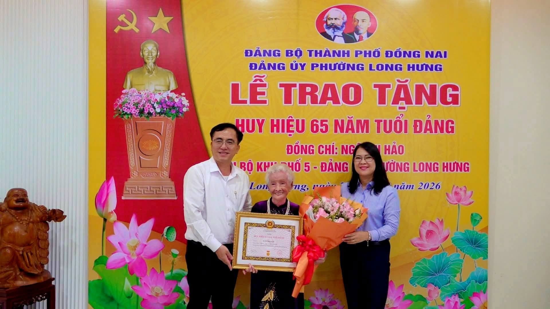 Đ/c Nguyễn Thị Như Ý - Thành ủy viên, Bí thư Đảng ủy, Chủ tịch HĐND phường Long Hưng và đ/c Kiều Minh Sinh - Phó Bí thư Thường trực Đảng ủy trân trọng trao Huy hiệu 65 năm tuổi Đảng cho đảng viên Ngô Thị Hảo